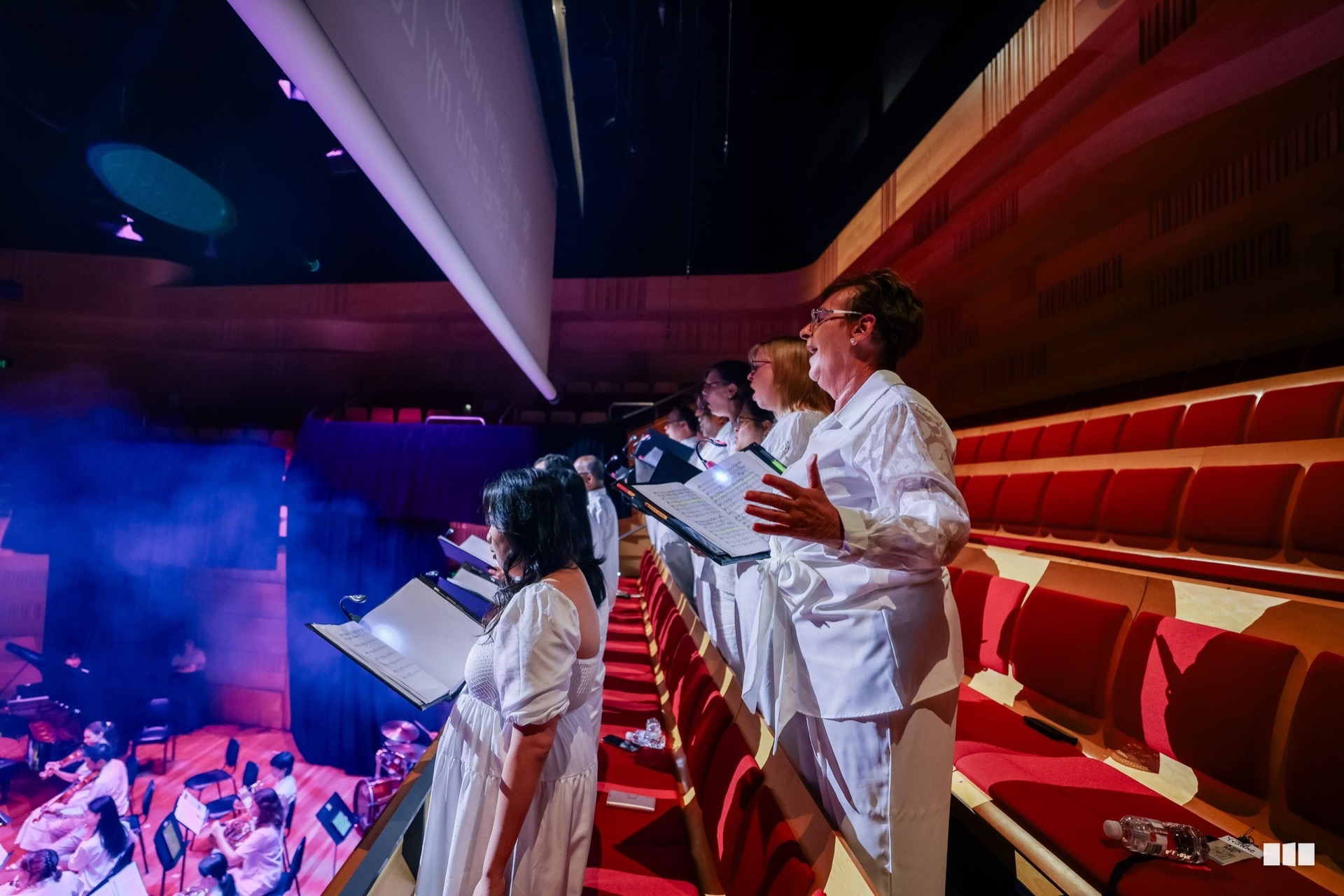 A vocalist performing from the balcony above the Australian Christian Orchestra in concert