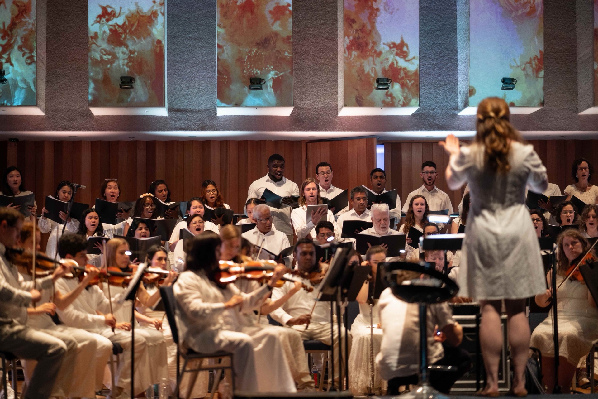 Conductor, choir and orchestra performing in a concert hall