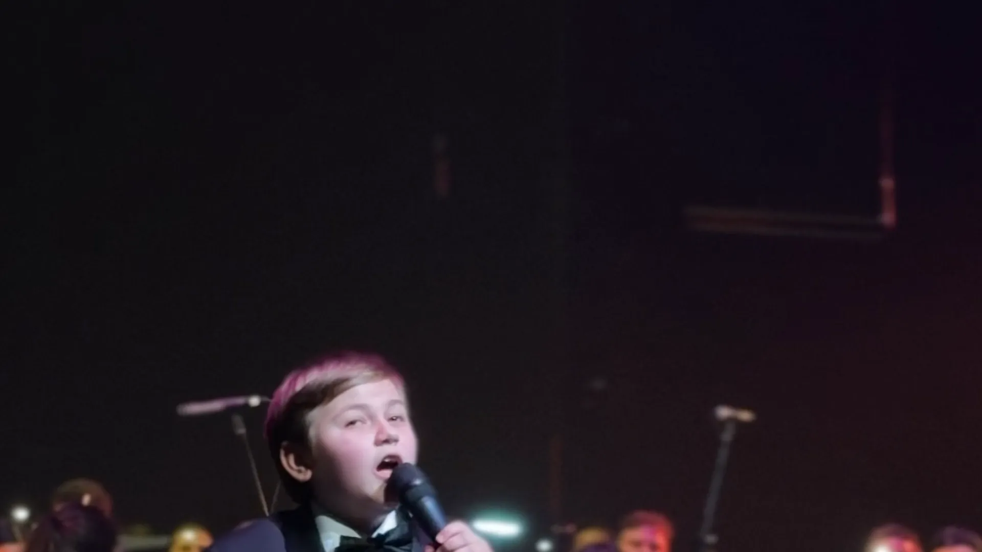 A young soloist singing with the orchestra behind him at the Australian Christian Proms
