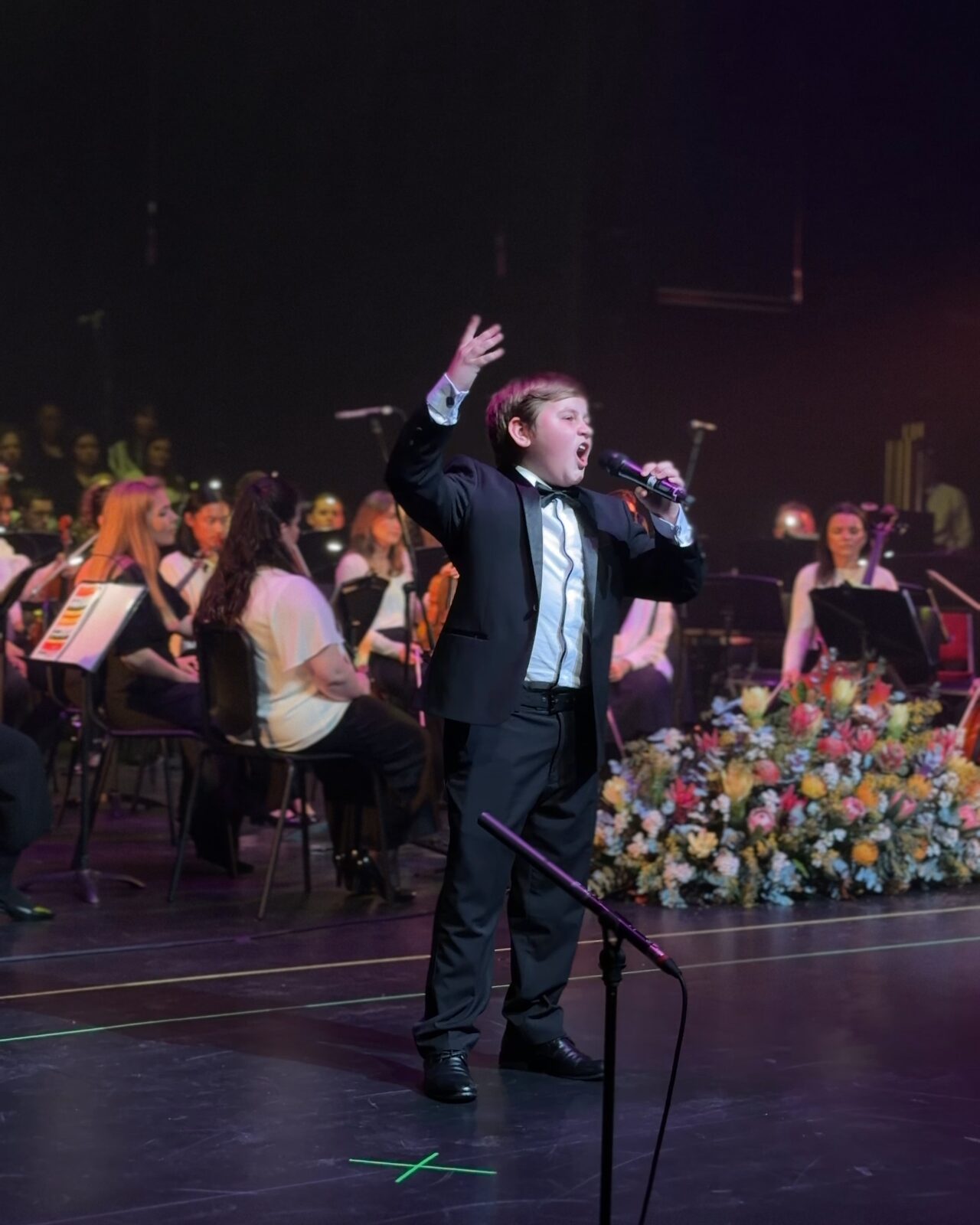 A young soloist singing with the orchestra behind him at the Australian Christian Proms, 2026