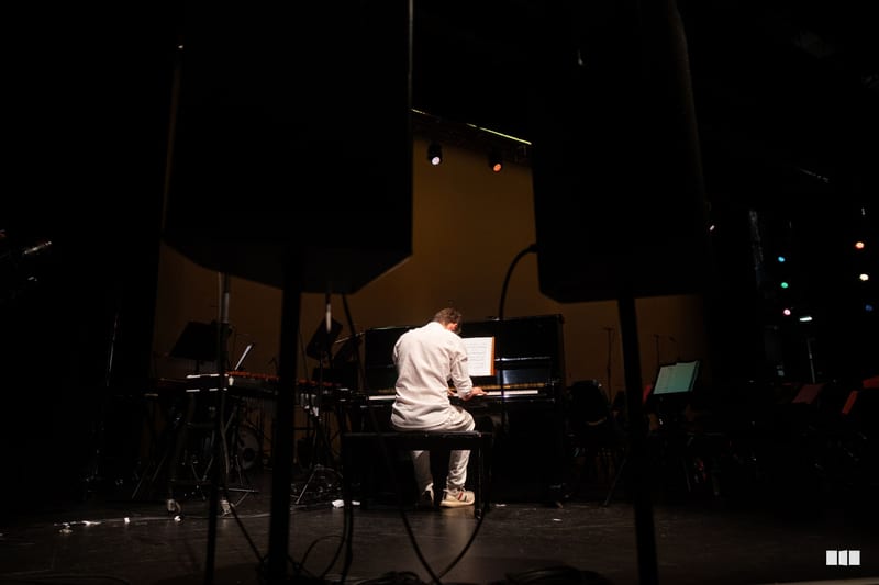 A pianist performs at the grand piano on stage during an evening concert.
