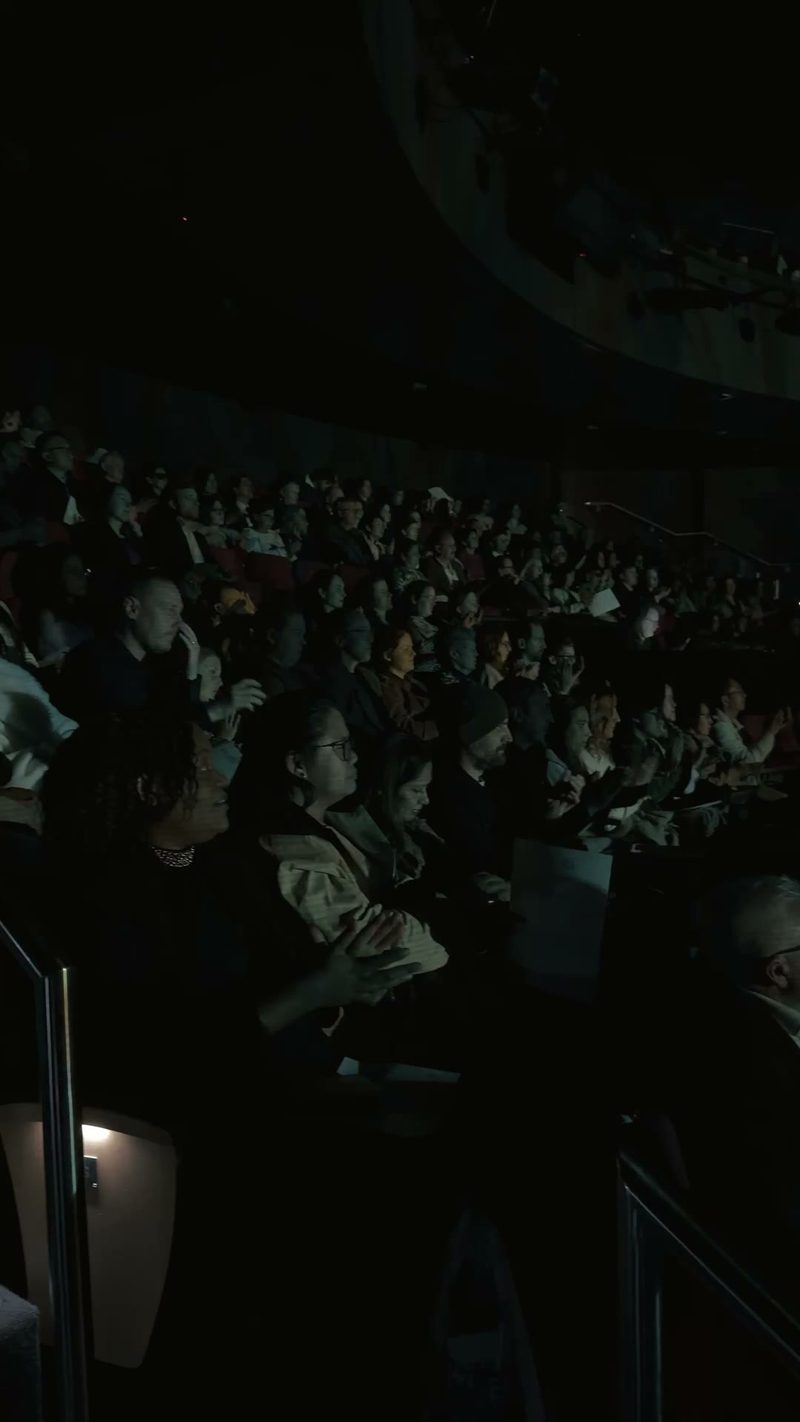 A diverse audience enjoying a performance in a dimly lit venue.