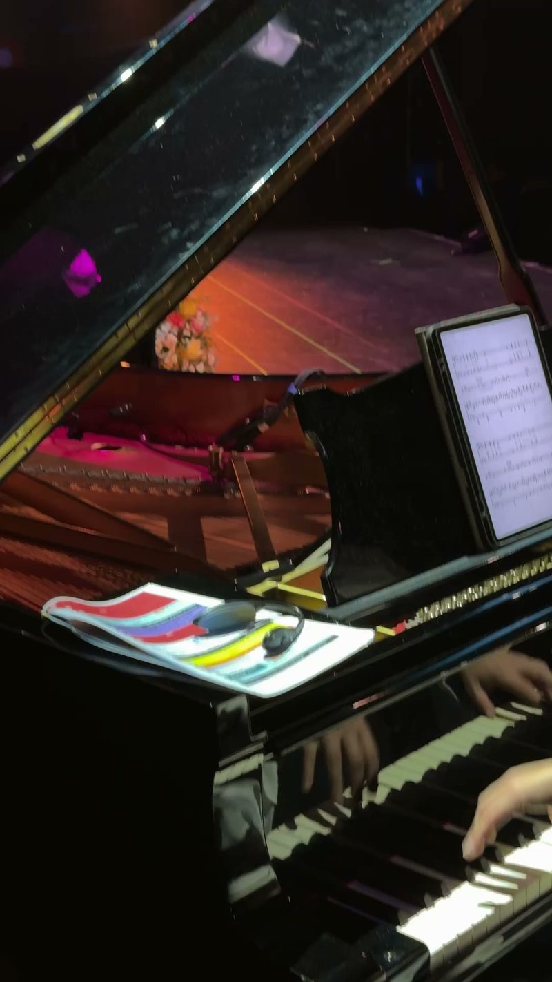 A close-up of a pianist's hands playing a grand piano with sheet music in view.