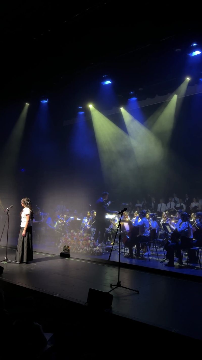 A soloist performing in front of a symphony orchestra during a concert.