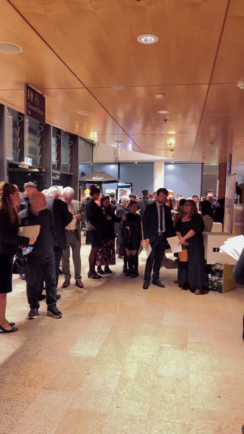 A crowd of people lines up in a public venue.