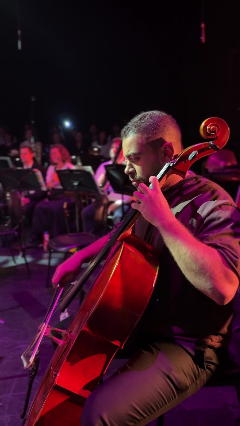 A musician performing with a cello in front of an audience.